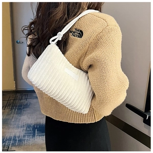 Detail view of white corduroy shoulder bag with knotted strap and textured surface