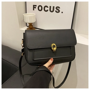 Détail du sac bandoulière noir mat avec boucle dorée à double anneau et coutures linéaires