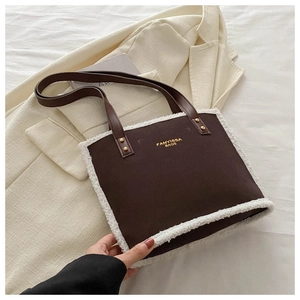 Detail of dark brown tote bag with white faux shearling trim and gold branding