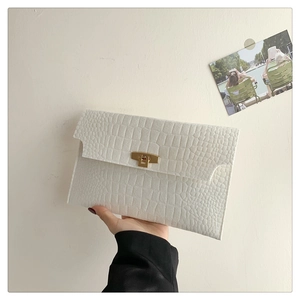 Close-up of white envelope clutch bag with crocodile texture and gold metal buckle
