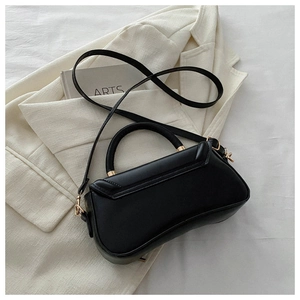 Close-up of black PU leather handbag with gold hardware on a white blazer background