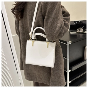 Detail of white leather handbag featuring gold metal hardware and detachable shoulder strap