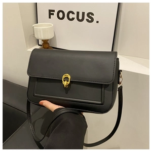 Détail d'un sac à bandoulière noir avec fermoir rond doré et coutures élégantes