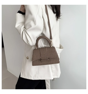 Brown woven texture crossbody bag shown styled with a white leather jacket