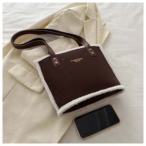 Chic brown suede tote with white faux fur trim styled on a beige blazer and smart phone