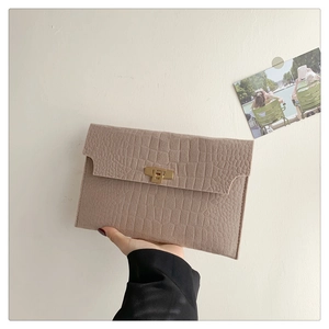 Detail shot of light khaki envelope bag featuring crocodile pattern and gold buckle
