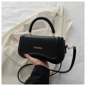 Close-up of black leather curved handbag with gold fashion lettering and handle detail