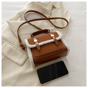 Detailed close-up of brown PU leather handbag with white faux fur trim and gold metal hardware