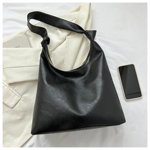 Close-up of black PU leather hobo bag featuring a unique knotted shoulder strap design
