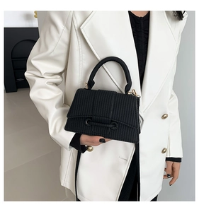 Detailed texture of black striped crossbody bag with elegant gold hardware and leather strap