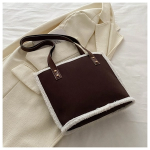 Detail of dark brown tote bag with white faux fur trim and vintage gold rivets on the strap