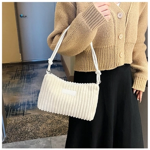 Close-up of white corduroy underarm bag with textured stripes and shoulder strap worn by model