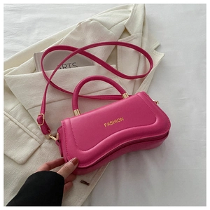 Close-up of a rose pink crescent handbag featuring gold FASHION text and elegant stitching
