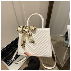 Detailed view of white chevron quilted crossbody bag with decorative silk scarf handle