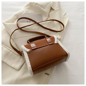 Detailed shot of brown leather bag with white plush trim on a beige suit background