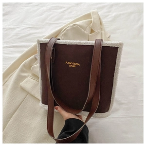 Detail of dark brown tote bag featuring plush white faux fur trim and gold logo