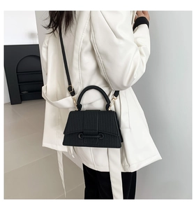Detailed texture of a black vintage crossbody bag with gold metal hardware and flap design