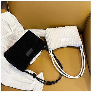 Detailed close-up of corduroy shoulder bags in black and cream on leather texture