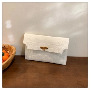 Close-up of white crocodile texture felt envelope clutch with gold metal buckle
