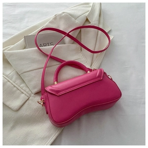 Detailed view of rose pink handbag with distinctive curved base on a white fabric background