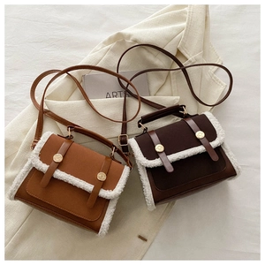 Close-up of winter crossbody bag with white plush trim and golden metal buckle details