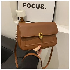 Détail d'un sac bandoulière marron en PU avec boucle ronde dorée et finitions soignées