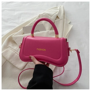 Detail of rose pink handbag featuring golden FASHION lettering and arched top handle
