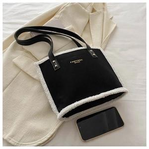 Detail of black tote bag featuring white faux fur trim and golden FANYISSA BAGS logo