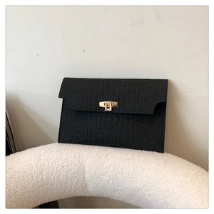 Detail view of a black crocodile-pattern envelope clutch with a gold rectangular metal lock