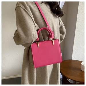Detailed side view of bright pink rectangular crossbody bag with elegant gold hardware