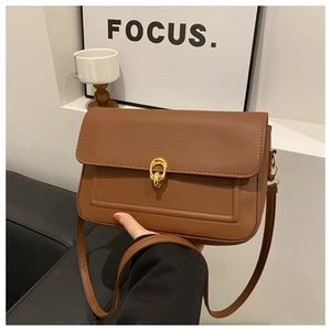 Détail d'un sac en cuir mat marron avec fermoir doré à double anneau et surpiqûres en U