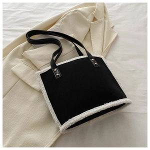 Detail of black faux leather shoulder bag with white fleece trim and gold rivets on the strap