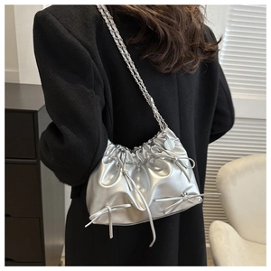 Detail of silver pleated bucket bag with metallic bows and chain shoulder strap