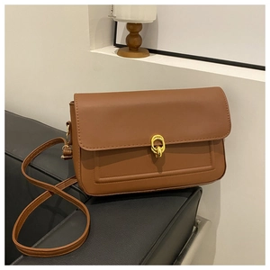 Détail du sac bandoulière marron caramel avec fermoir doré rond et coutures précises