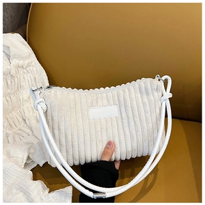 Close-up of white corduroy shoulder bag showing ribbed texture and knotted strap detail