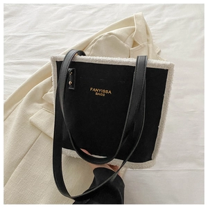 Detail of black tote bag with white faux shearling trim and gold logo lettering