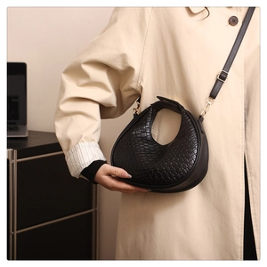 Dettaglio della borsa hobo intrecciata nera con texture fine e fibbia in metallo dorato