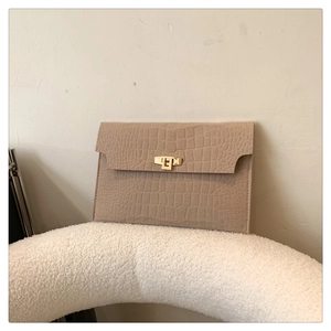 Detail of warm brown envelope clutch with crocodile texture and gold square turn-lock