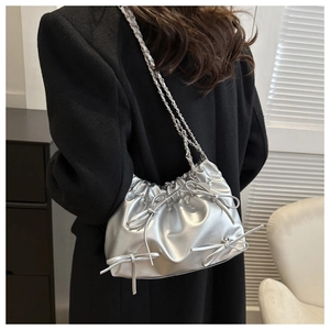 Close-up of silver pleated tote bag with bow details and metallic chain strap