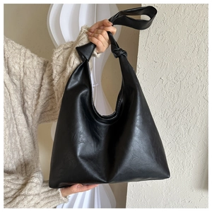 Detailed view of black soft leather shoulder bag featuring a unique knotted strap design