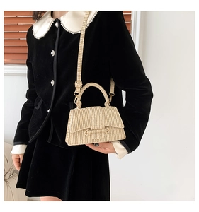 Detailed view of beige woven trapezoid handbag with top handle and detachable strap