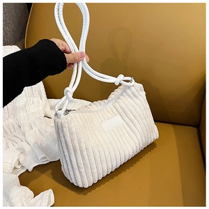 Detail of white corduroy shoulder bag showing vertical rib texture and knotted handle