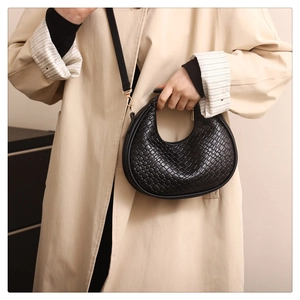 Detail shot of the black woven texture and gold metal hardware on the crescent bag
