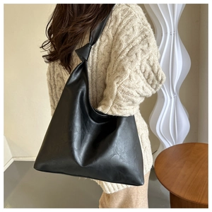 Detail of a black textured hobo bag with a distinctive knot shoulder strap design
