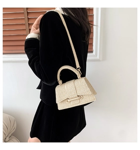 Detailed texture of a cream woven straw crossbody bag with a sturdy top handle