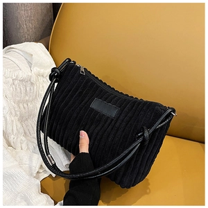 Detail of black corduroy shoulder bag showing vertical rib texture and knotted strap