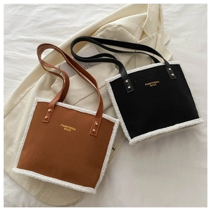 Detail view of brown and black shearling patchwork tote bags on a beige blazer