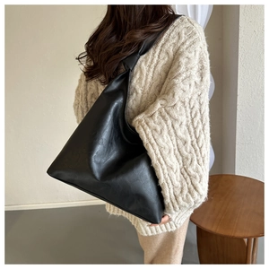 Detail of soft black faux leather tote featuring a stylish knot design on the shoulder strap