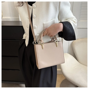 Close-up of minimalist apricot crossbody bag with elegant stitching and gold metal hardware