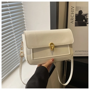 Détail du sac en cuir blanc crème montrant le fermoir doré et la structure à rabat lisse